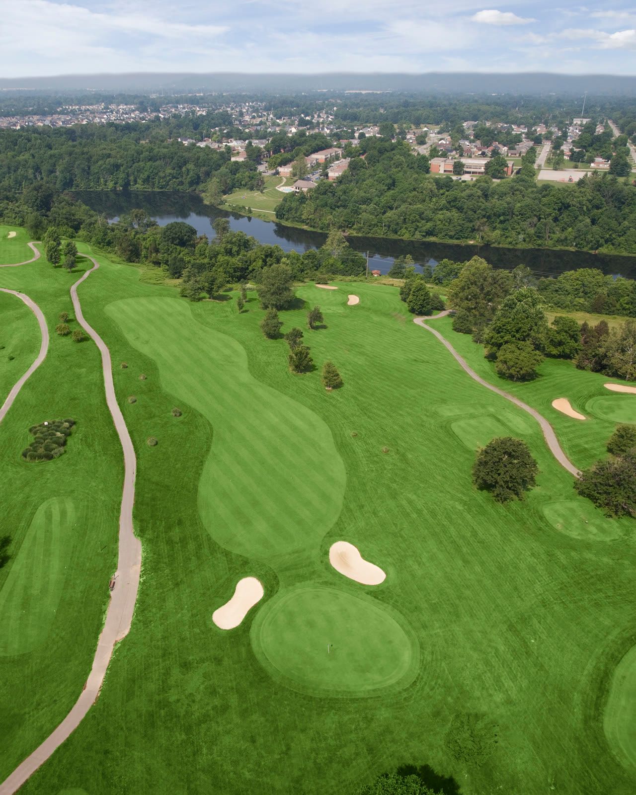 Aerial view of Quail Chase greens and bunkers with a lake in the distance